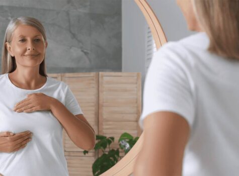 Frau vor dem Spiegel betrachtet ihre Brust
