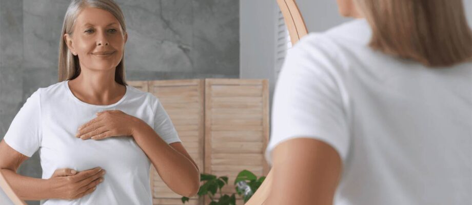 Frau vor dem Spiegel betrachtet ihre Brust